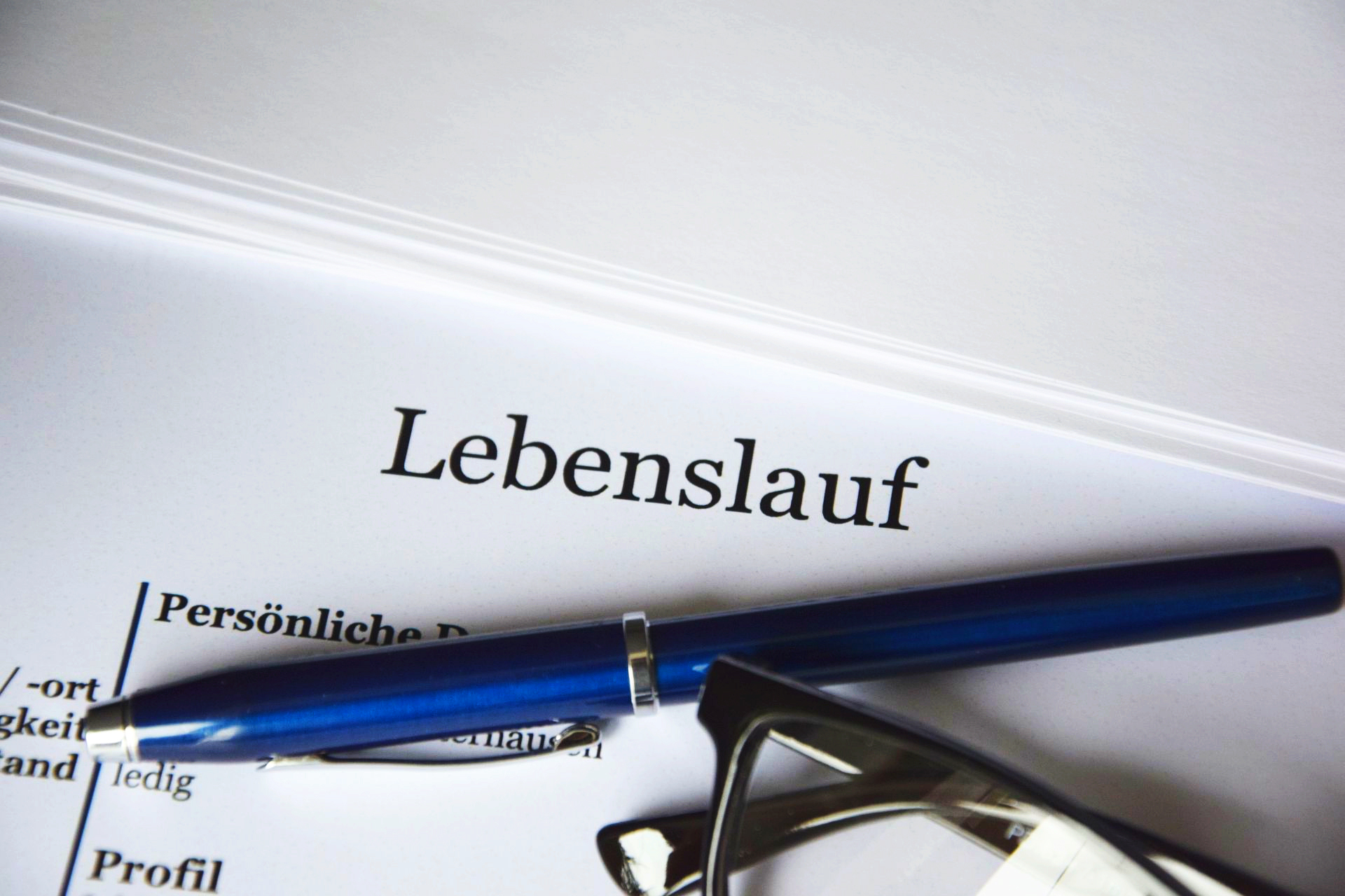 Brille, Kugelschreiber und Zettel mit Titel "Lebenslauf"